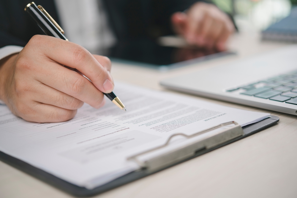 Image of a hand holding a pen filling out a form.