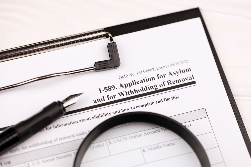 Image of Form I-589 on a clipboard with a pen.