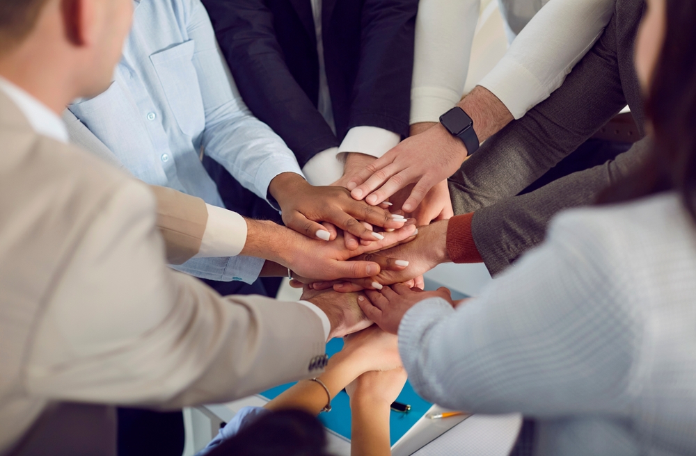 Image of professionals joining hands in solidarity.