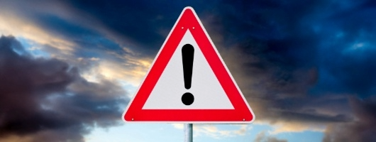 Storm clouds with a WARNING road sign in front of them.